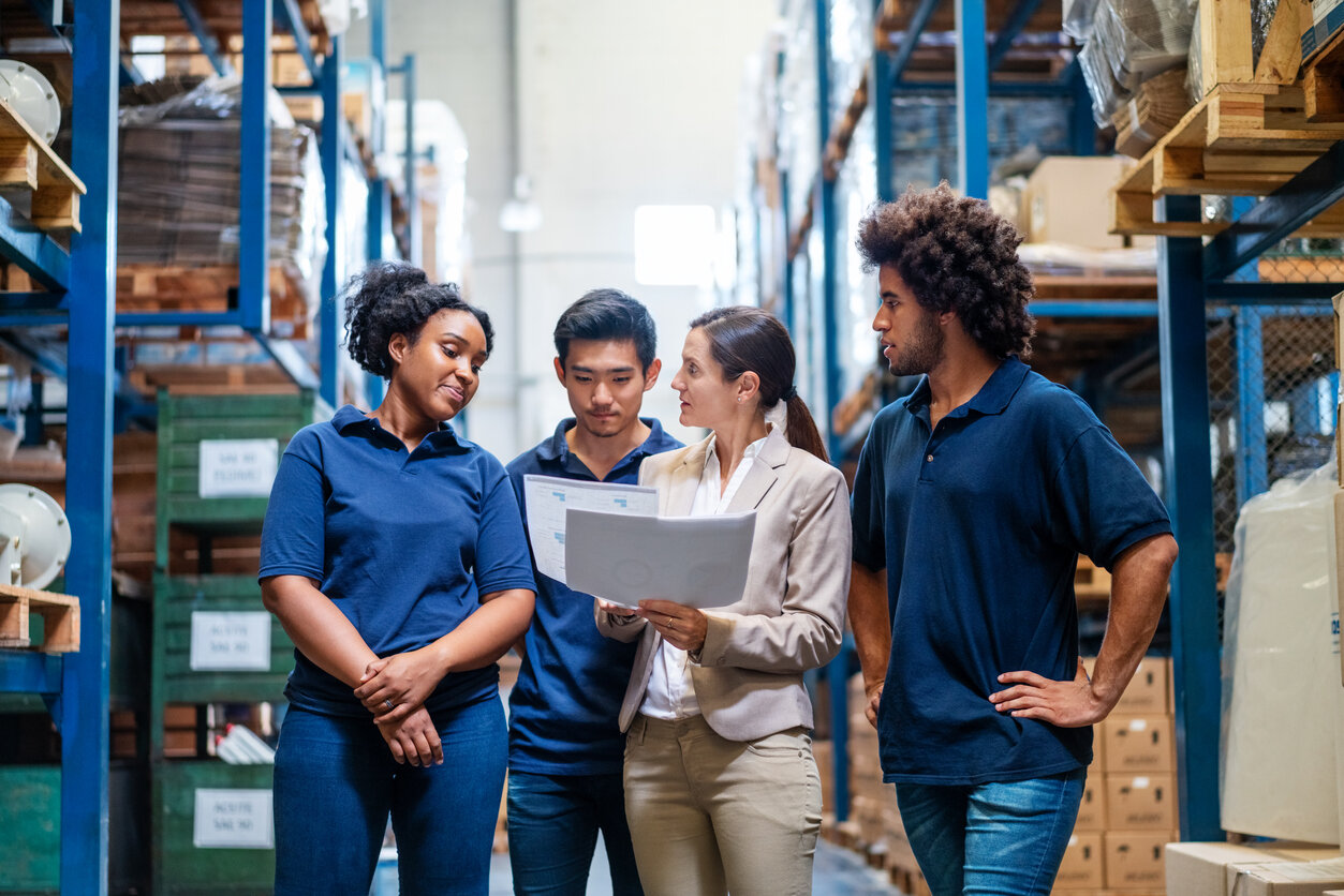 Female manager discussing logistics, delivery schedules, and planning for the holiday surge with the staff in warehouse.