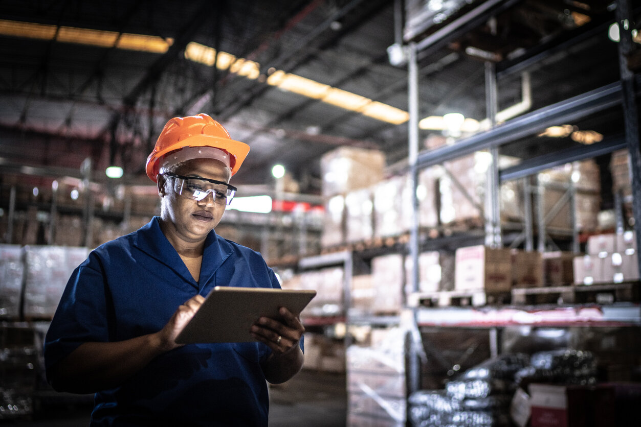 Female worker walking and using digital tablet with NetSuite and WMS Integration in a warehouse