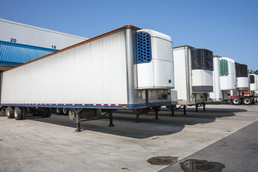 Refrigerated truck trailers lined up at a distribution warehouse.