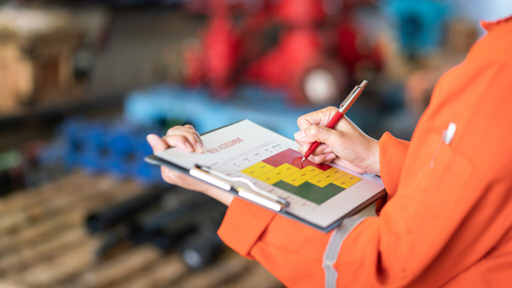 Close-up and selective focus of a person holding a pen and a clipboard in a warehouse for inventory forecasting.