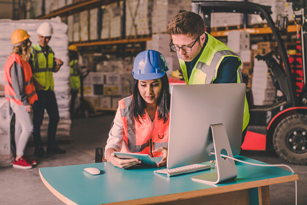 Two workers discussing inventory and logistics solutions in a designated 3PL warehouse on a computer and tablet