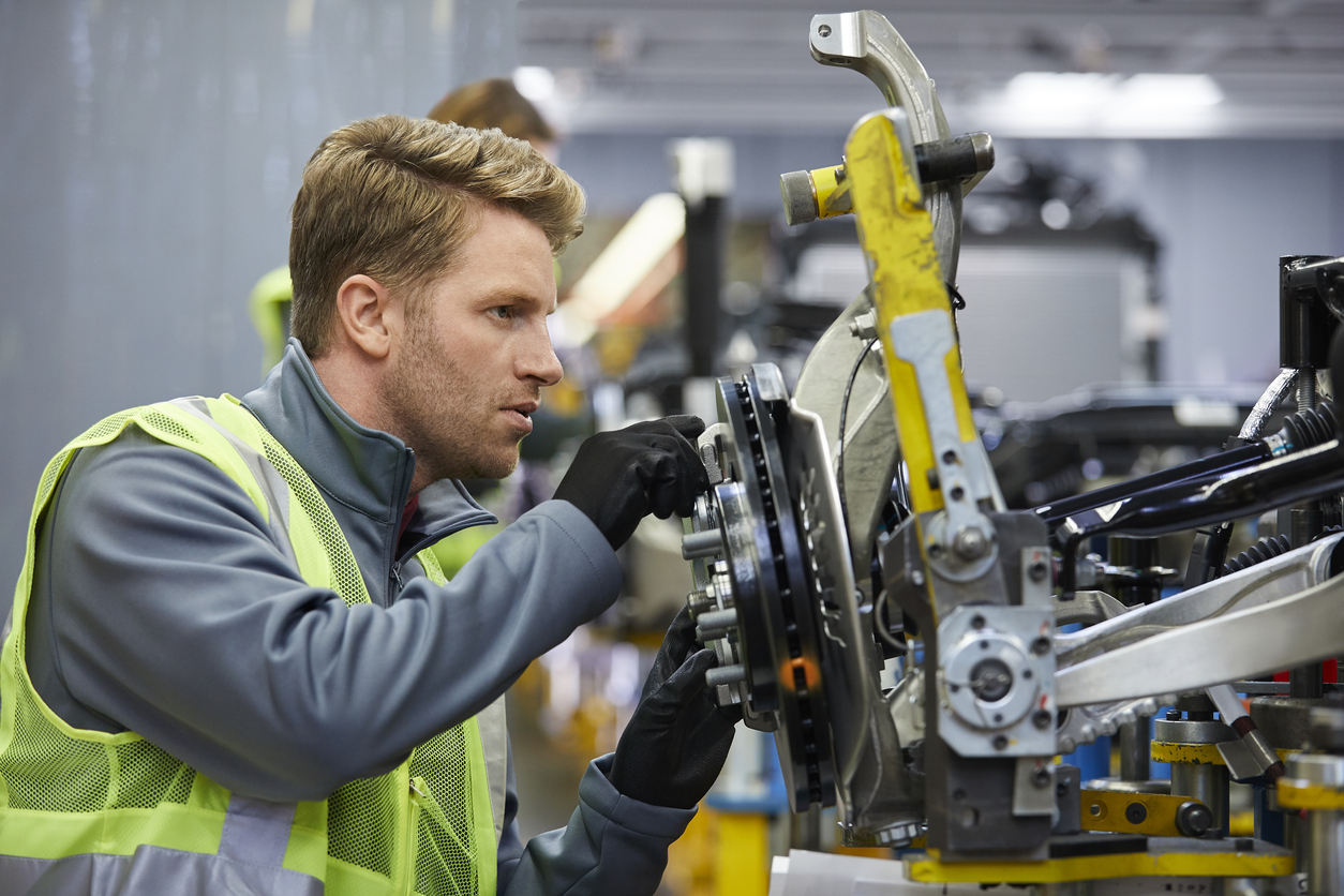 Man examining car chassis at an auto parts fulfillment warehouse.