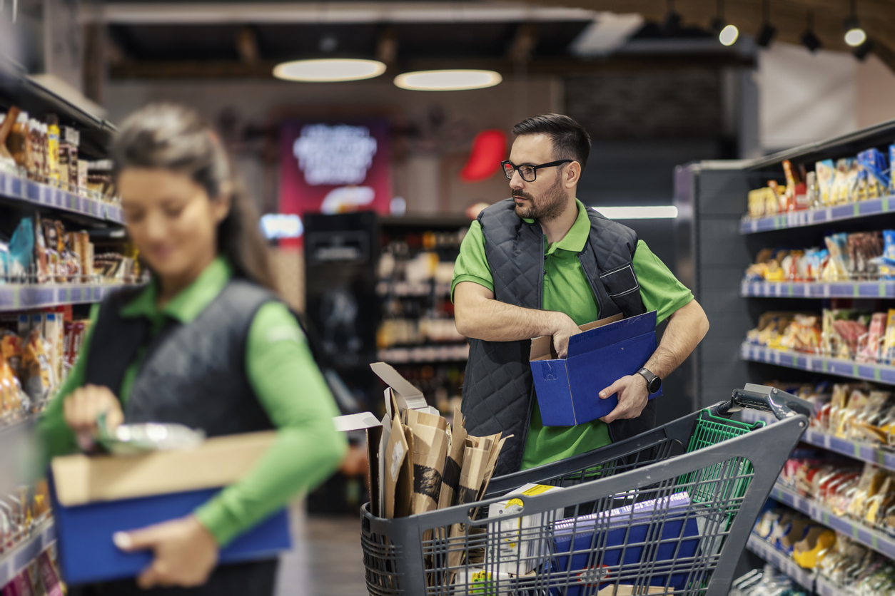 Two grocery workers stocking products from suppliers with SQF certification