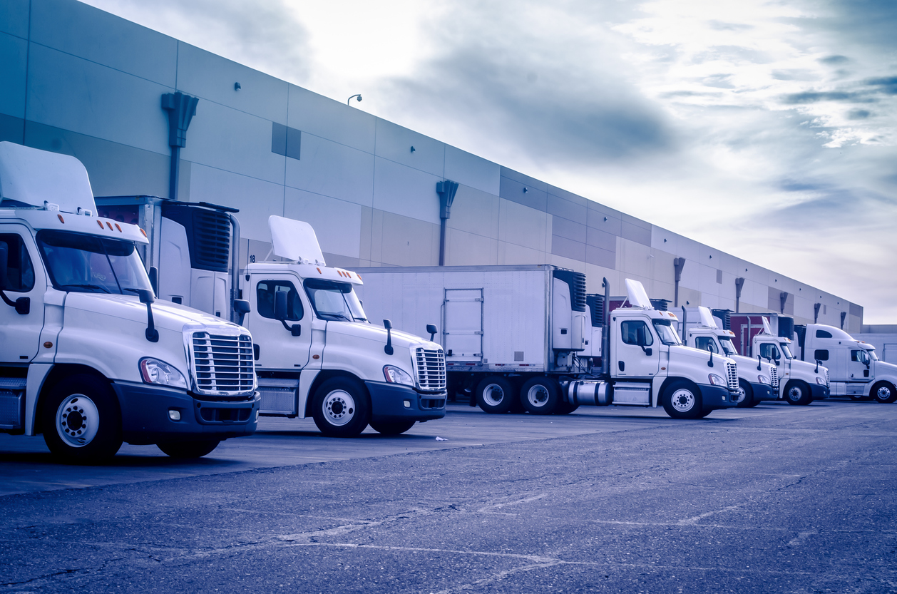 Trucks loading and unloading at a warehouse, representing the transportation and delivery processes managed by logistics providers.