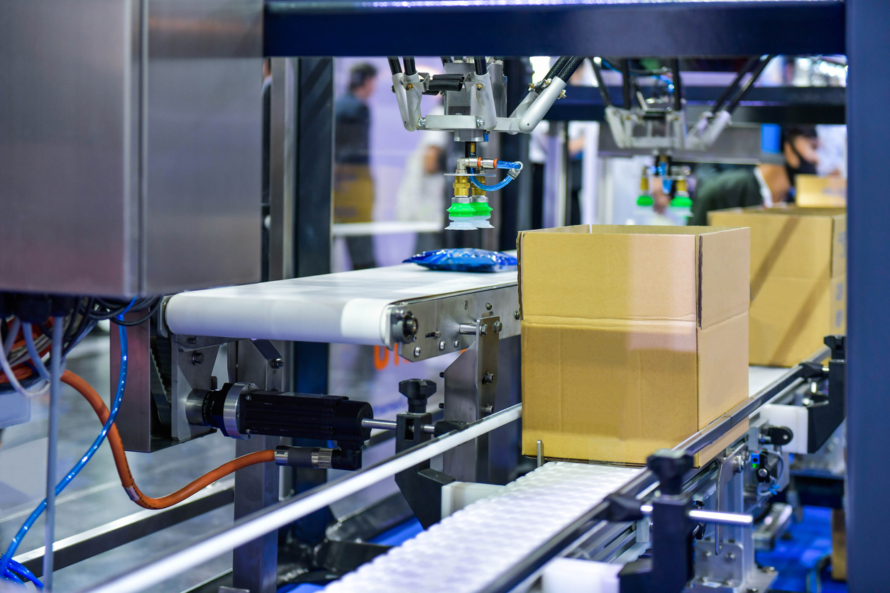 Cardboard boxes on a conveyor belt, representing the automation of the kitting process in order fulfillment systems