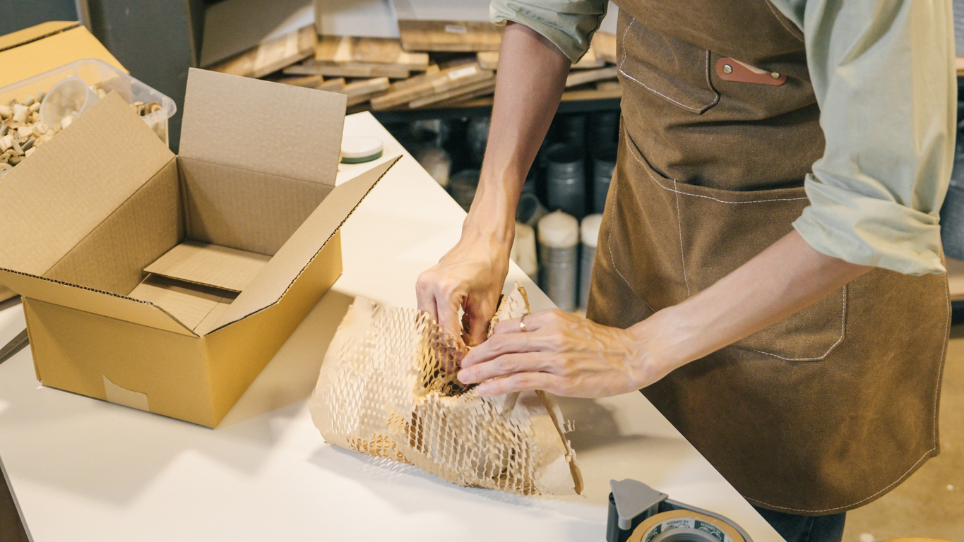 A small business warehouse worker packing products with eco-friendly materials, emphasizing the efficiency and sustainability of the kitting process