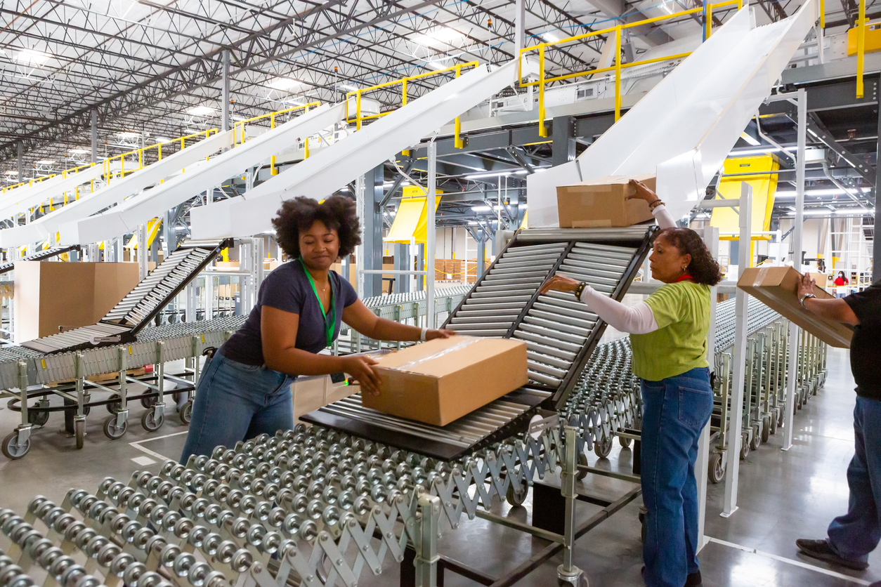 Fulfillment center employees pushing boxes along rollers into a truck, symbolizing the teamwork and support behind successful fulfillment partnerships