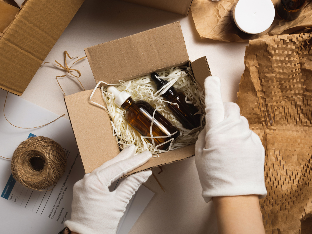 Beauty box with serum bottles on shredded white paper, showcasing an example of the kitting process for health and beauty products