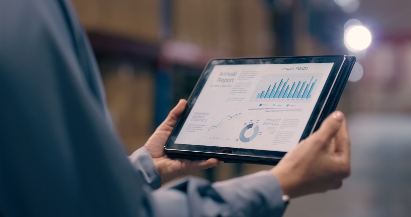 Hands holding a tablet displaying inventory management data in a warehouse, illustrating how adopting advanced technology in 3PL operations enhances efficiency and bolsters brand reputation.