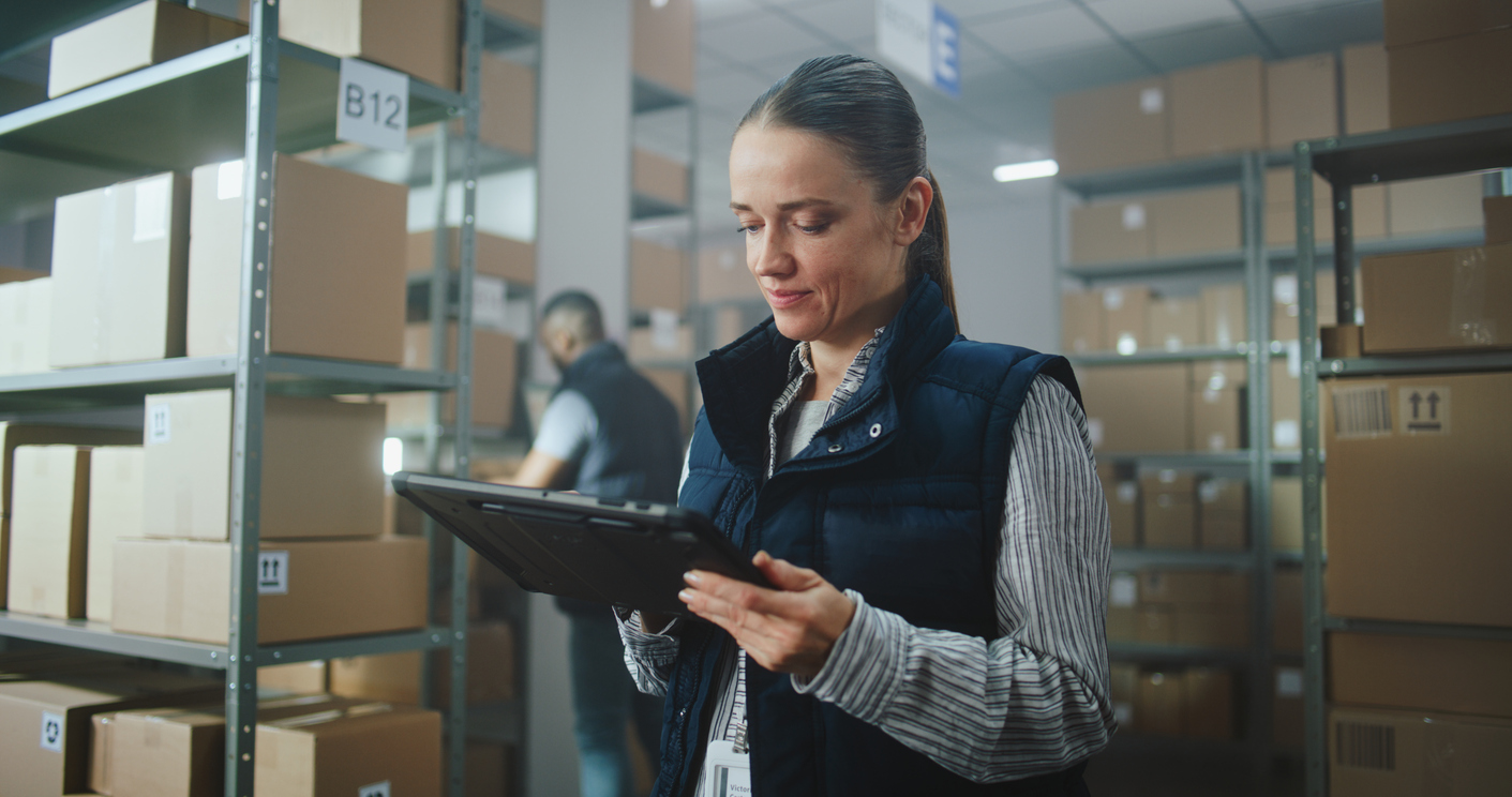 Inventory manager in warehouse using a tablet to track stock for education fulfillment services