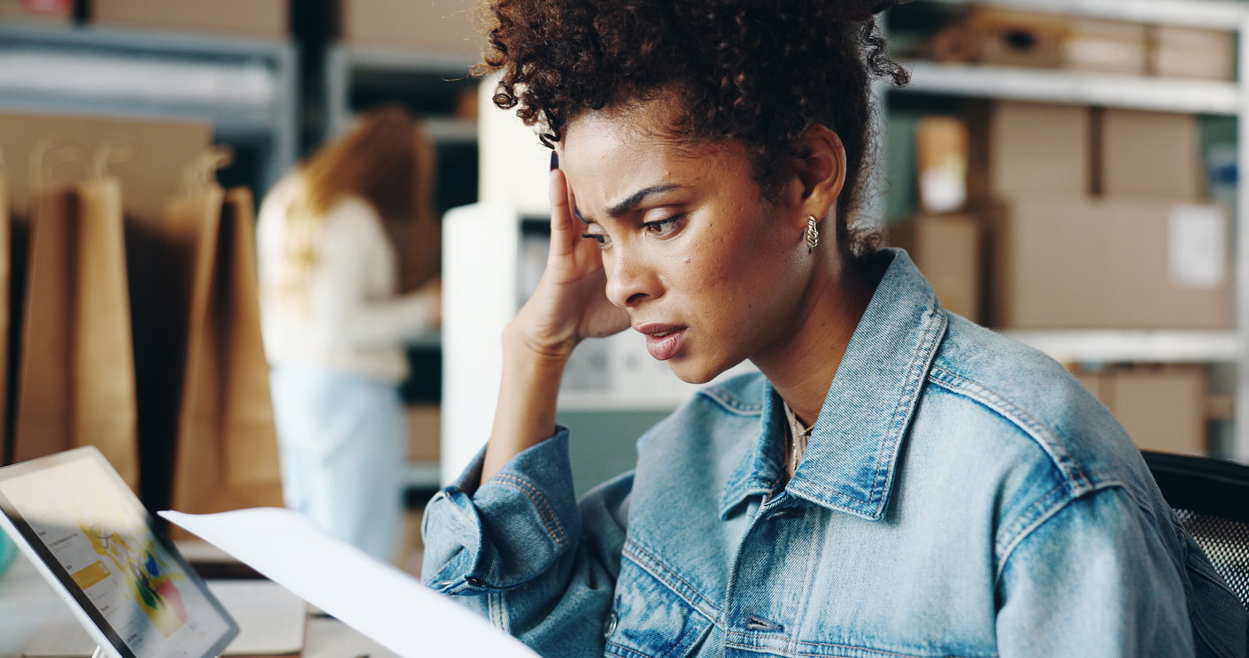 Stressed business owner reviewing shipping reports and costs on a laptop, highlighting the impact of rising parcel costs.