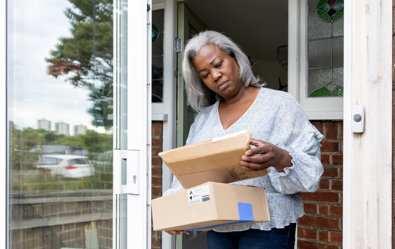 Woman at home receiving multiple packages and looking confused, representing delivery uncertainty and its effect on fulfillment strategy.