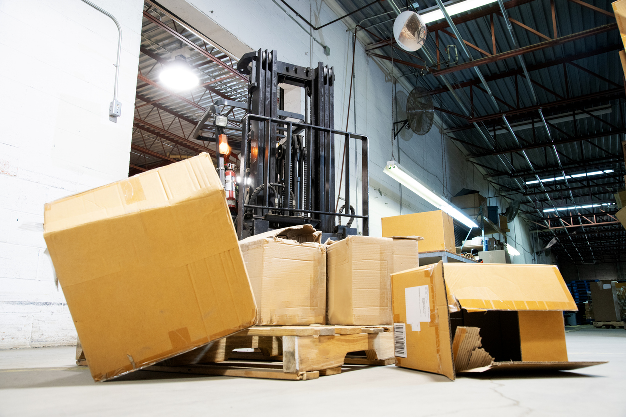 Damaged boxes fallen off a forklift in a warehouse, illustrating inventory loss scenarios relevant to warehouse legal liability insurance.