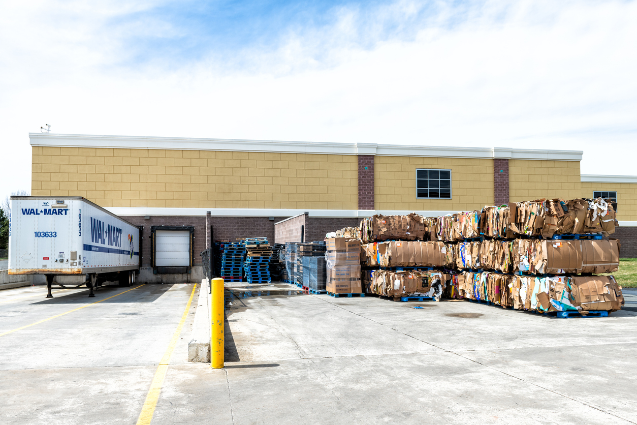 Walmart semi truck trailer tractor loading dock station, container with stacks, piles of many stacked boxes illustrating Walmart’s logistics infrastructure and big-box fulfillment operations.