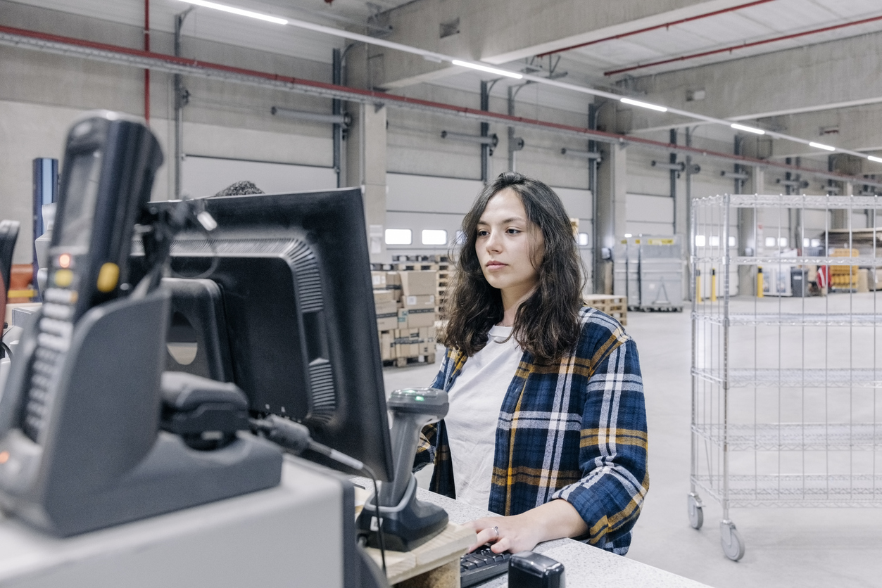Female warehouse employee viewing inventory on computer with visibility across the supply chain in distribution warehouse, illustrating fulfillment visibility and tracking.