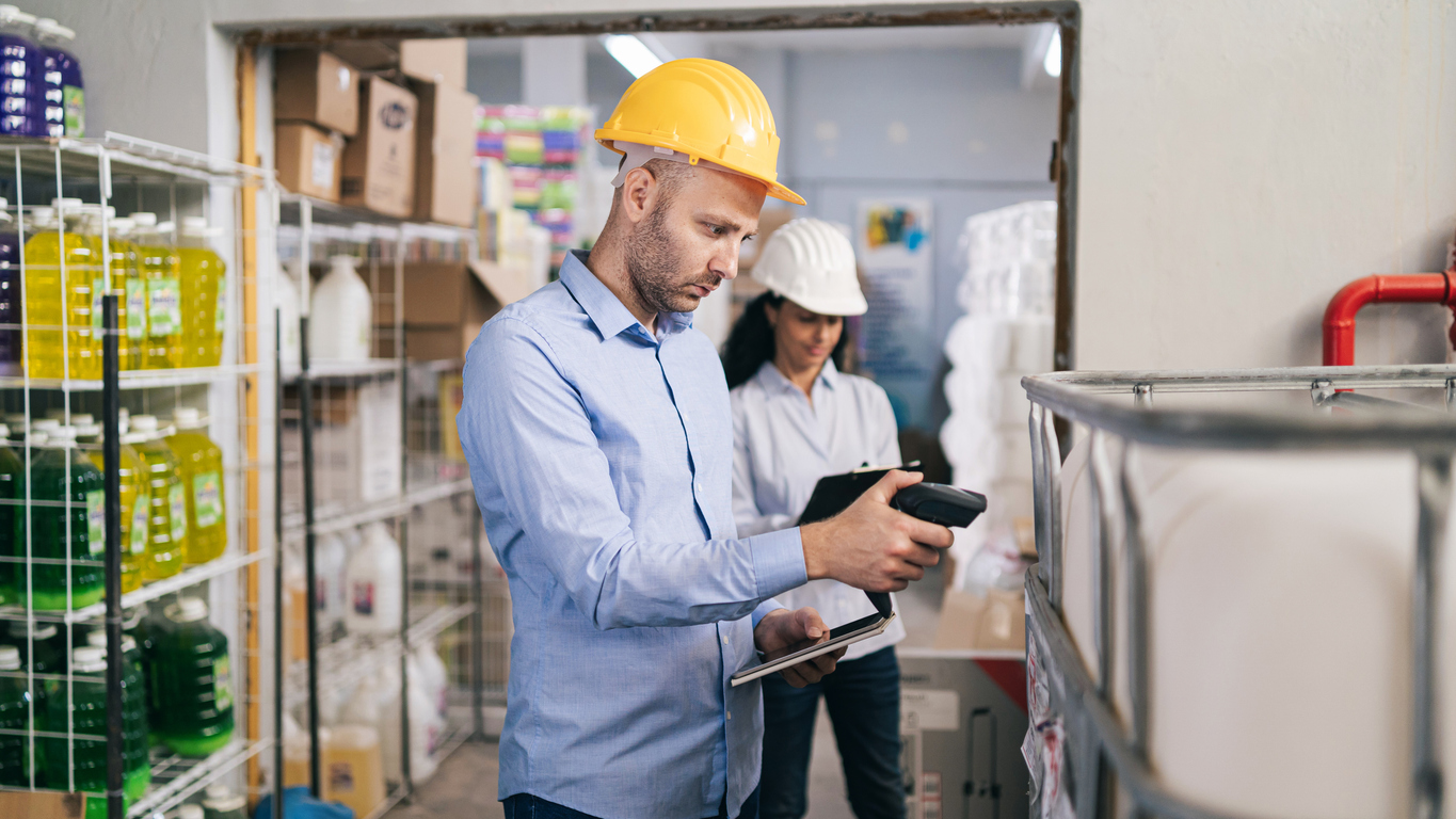 Male worker holding RFID scanner and scanning a parcel barcode in a delivery warehouse, illustrating smart labeling and enhanced fulfillment visibility.
