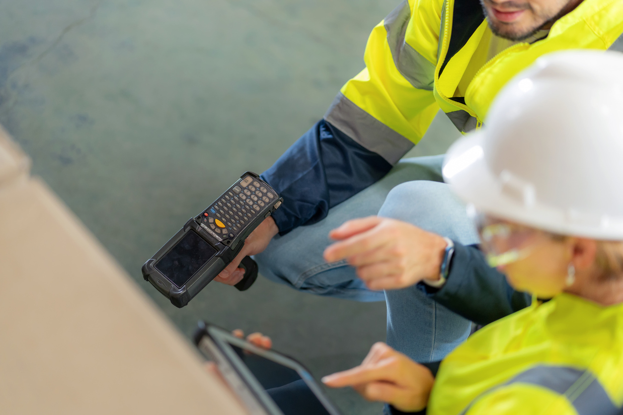 Warehouse workers in protective gear scanning barcodes to ensure on-time, in-full deliveries and maintain supply chain KPIs.