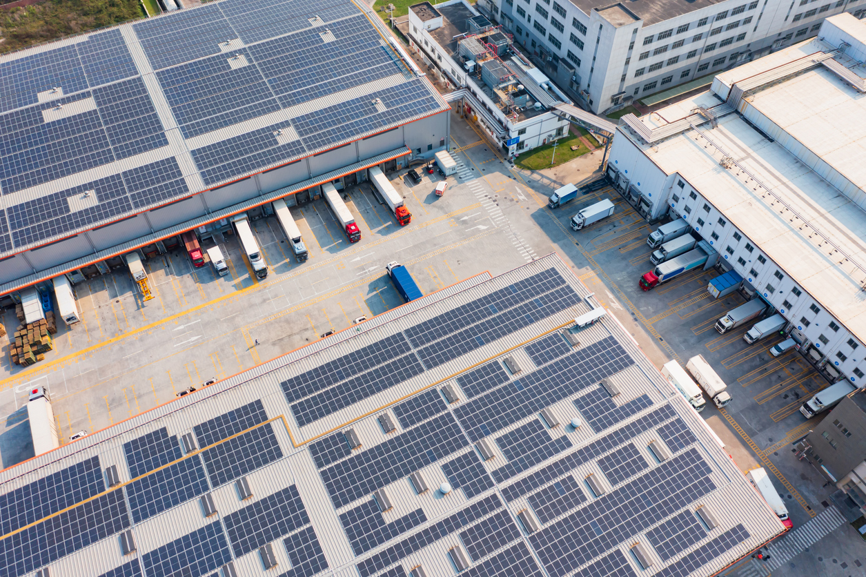 Aerial view of a sustainable logistics park with solar-panel roofs and efficient truck routing, representing environmental KPIs in supply chain operations.